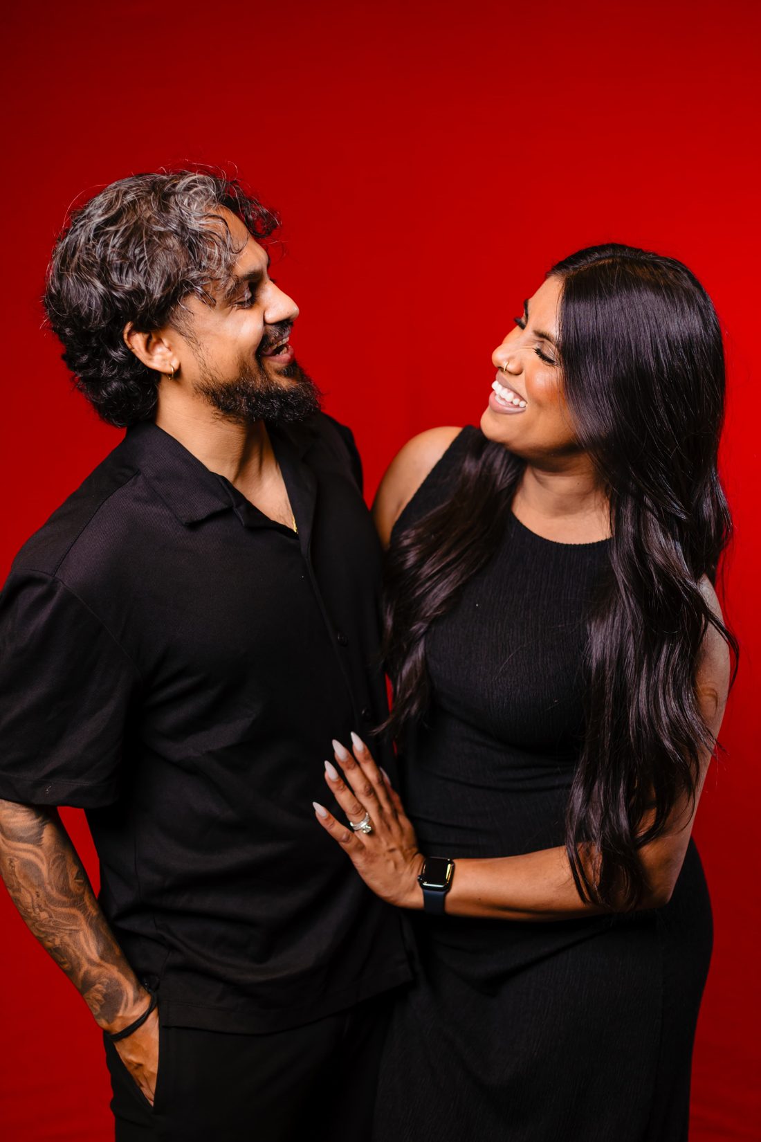 Gnan and Stephanie laughing together in front of a red backdrop